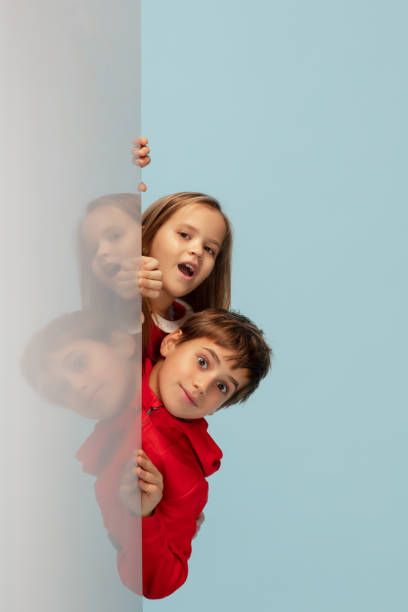 istock Happy children isolated on blue studio background. Look happy, cheerful, sincere. Copyspace. Childhood, education, emotions concept 1298288397