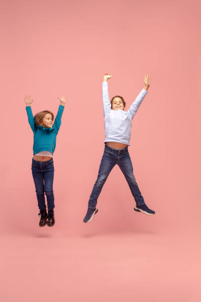 istock Happy children isolated on coral pink studio background. Look happy, cheerful, sincere. Copyspace. Childhood, education, emotions concept 1298288421