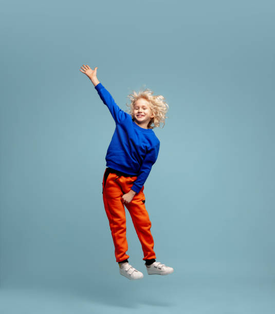 istock Happy curly boy isolated on blue studio background. Looks happy, cheerful, sincere. Copyspace. Childhood, education, emotions concept 1298288428