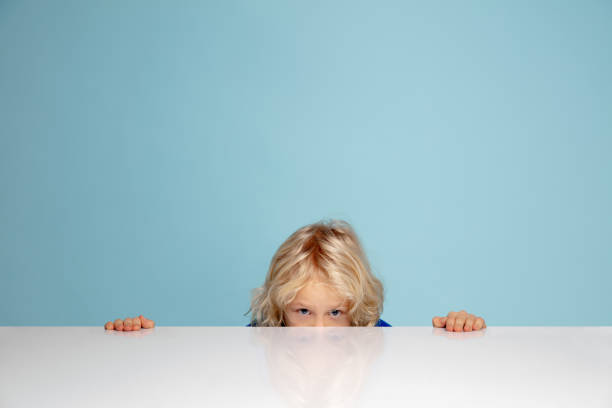 istock Happy curly boy isolated on blue studio background. Looks happy, cheerful, sincere. Copyspace. Childhood, education, emotions concept 1298288441