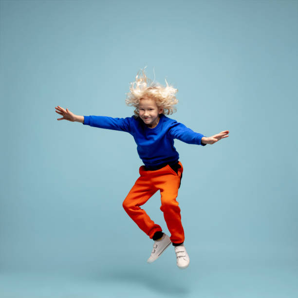 istock Happy curly boy isolated on blue studio background. Looks happy, cheerful, sincere. Copyspace. Childhood, education, emotions concept 1298288444