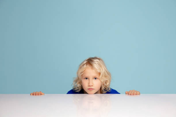 istock Happy curly boy isolated on blue studio background. Looks happy, cheerful, sincere. Copyspace. Childhood, education, emotions concept 1298288455