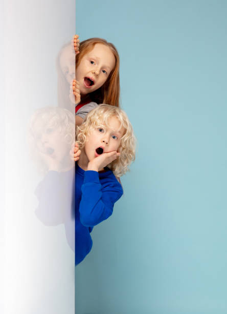 istock Happy children isolated on blue studio background. Look happy, cheerful, sincere. Copyspace. Childhood, education, emotions concept 1298288464