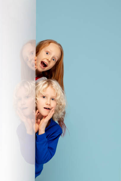 istock Happy children isolated on blue studio background. Look happy, cheerful, sincere. Copyspace. Childhood, education, emotions concept 1298288470