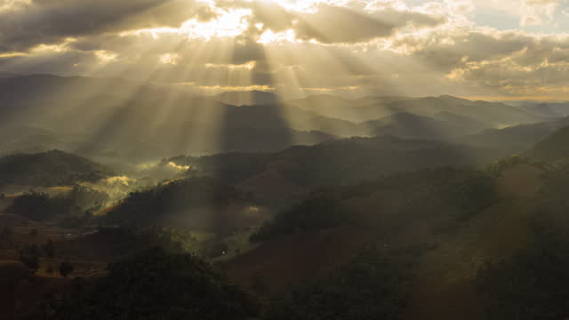 山岳地帯の風景で曇り空から太陽の光ビームのドローンタイムラプスの空中写真の経過。