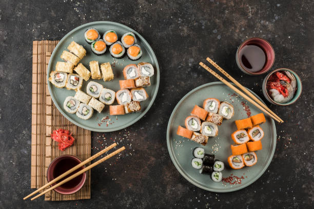 istock Two large sets with sushi rolls served by the chef on a dark background. 1298290891