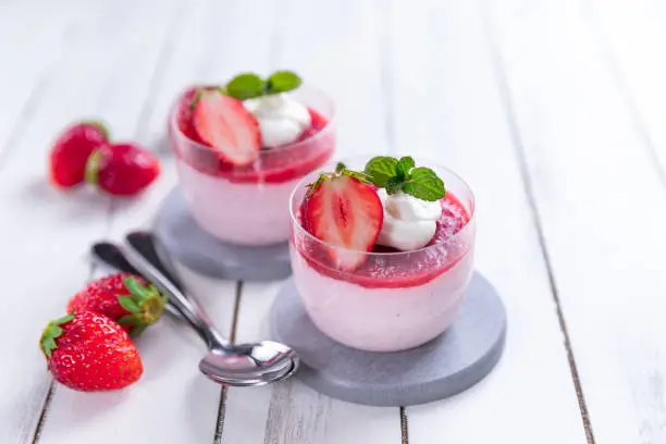 Homemade strawberry mousse in a glass on an old white rustic wooden table