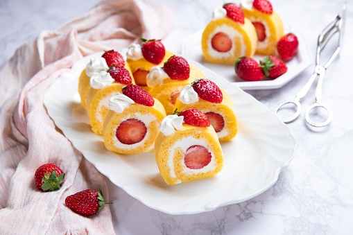 Homemade strawberry shortcake cake roll with cream cheese whipped cream, perfect summer season dessert served on marble board