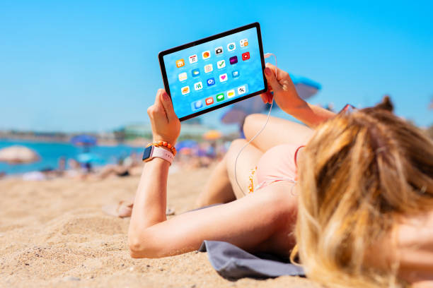 istock Woman using tablet computer while relaxing and sunbathing in bikini on the beach in hot summer day 1298295045