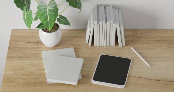 istock 3d render Working desk with white background. tablet, pencil, white blank book and green plant on wood table. minimal workspace. wall interior design concept template. 1298295850