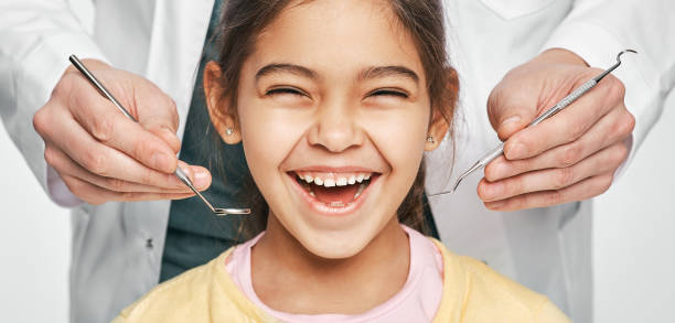 fille mélangée de course de sourire dans une clinique dentaire pour des enfants. enfant avec un sourire denté pendant l’inspection de la cavité buccale par un dentiste. plan rapproché - hygiene dental hygiene human teeth child photos et images de collection