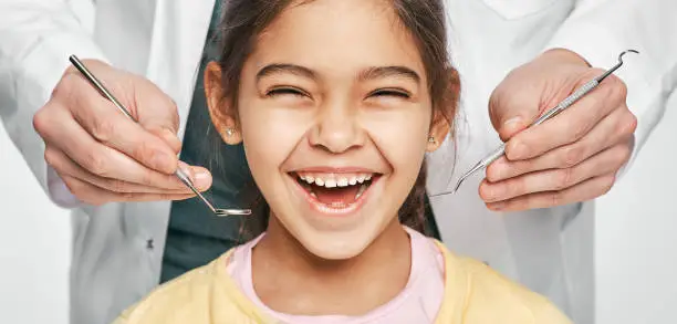 Photo of Smiling mixed race girl in a dental clinic for children. Child with a toothy smile during inspection of oral cavity by a dentist. Close-up