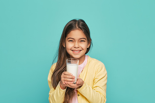 Asian little cute kid holding a cup of milk in the house. feel happy and enjoy drinking milk.
