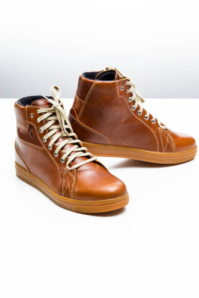 istock Pair of New Leather Tan Motorcyclist Boots Against White Background. Vertical image Composition 1298297643