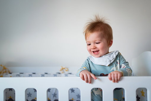 Smiling Caucasian baby boy in a crib.