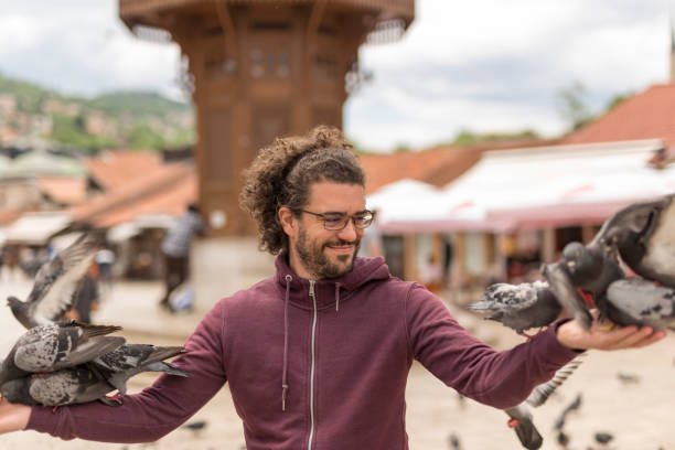 istock Man holding arms spread while flock of pigeons are eating from his hands 1298299814