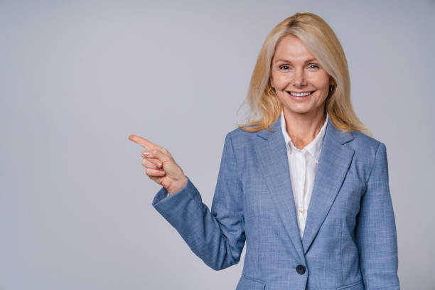 istock Confident middle-aged business woman pointing at copy space isolated over grey background 1298301885