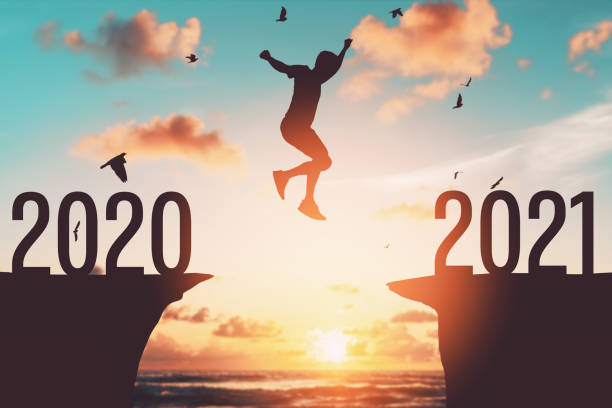 istock Silhouette man jumping between cliff with number 2020 to 2021 at tropical sunset beach. 1298303071
