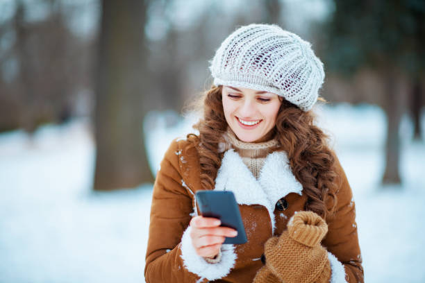 istock smiling woman using phone app outdoors in city park in winter 1298303833