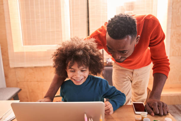 istock Daddy helping to his little son studying online at home 1298305676