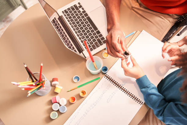 istock Kid drawing with paints on paper while sitting at the table 1298305738