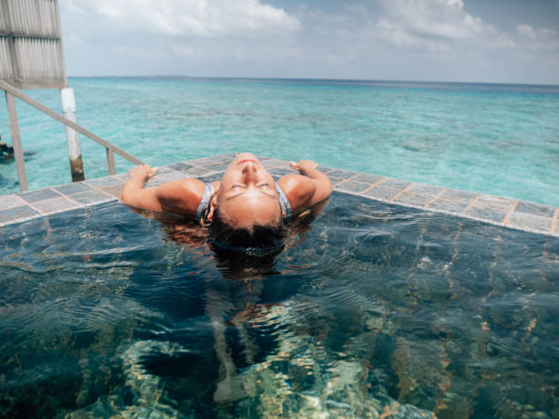 istock Woman relaxes inside infinity pool over reef lagoon 1298305969