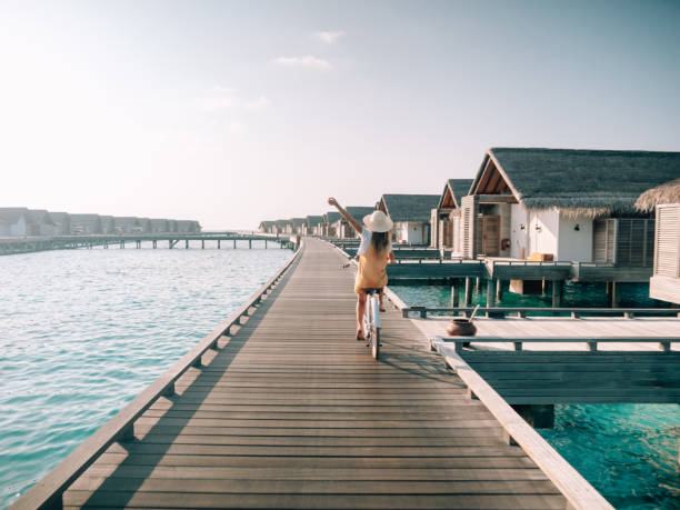 モルディブの木製桟橋で自転車に乗っている若い女性 - touristic resort ストックフォトと画像