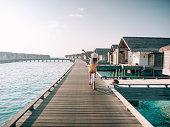 istock Young woman riding bicycle on wooden pier in the Maldives 1298306226