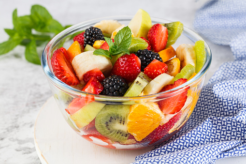 Healthy fresh fruit salad in a bowl on a gray background.