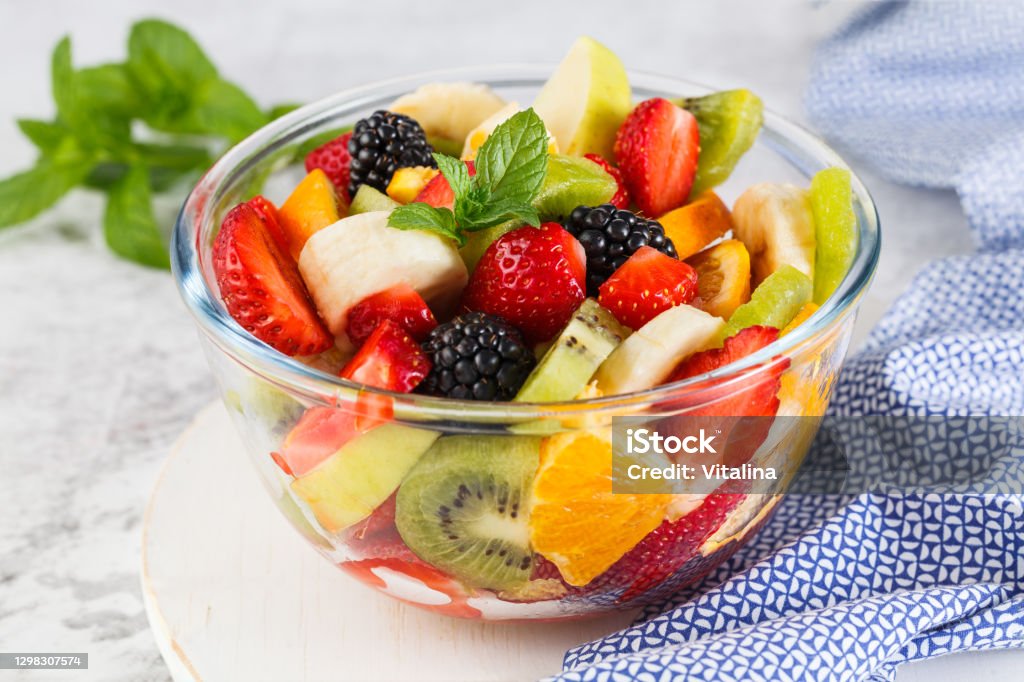 Delicious fruit salad on a plate on table. Healthy fresh fruit salad in a bowl on a gray background. Fruit Stock Photo