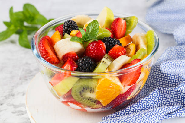 Delicious fruit salad on a plate on table. Healthy fresh fruit salad in a bowl on a gray background. fruits stock pictures, royalty-free photos & images