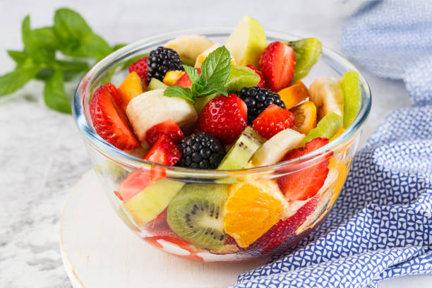 Delicious fruit salad on a plate on table. Healthy fresh fruit salad in a bowl on a gray background. fruit stock pictures, royalty-free photos & images