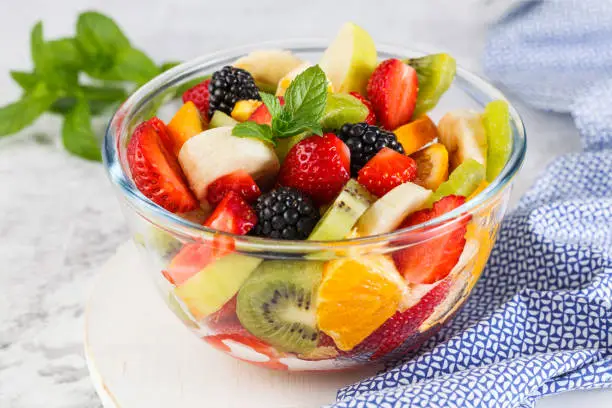 Healthy fresh fruit salad in a bowl on a gray background.