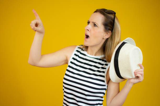 istock Surprised woman pointing up with index finger while smiling cheerfully away, standing over yellow background. 1298309829