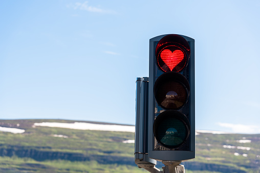 Close up of traffic lights with a red heart-shaped signal in Akureyri, Iceland, on a clear summer day