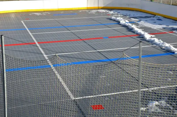 ice stadium for playing hockey with remnants of snow in the spring. plastic grates are visible under which the cooling medium flows in the pipes. warm winters and coronavirus stopped the sport. catching white guardrails and nets to capture the puck