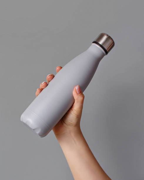 istock Hand with grey rinsulated bottle on grey background 1298312786
