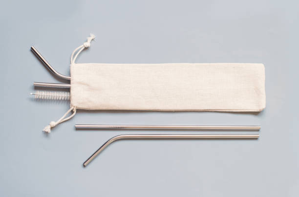 Reusable stainless steel straws and cleaning brush with cream cotton bag on grey background. Reusable stainless steel straws and cleaning brush with cream cotton bag on grey background. Eco friendly lifestyle concept straw stock pictures, royalty-free photos & images