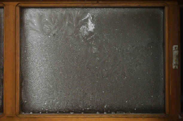 istock Frost patterns on the window in a wooden frame. Cold winter. 1298314494