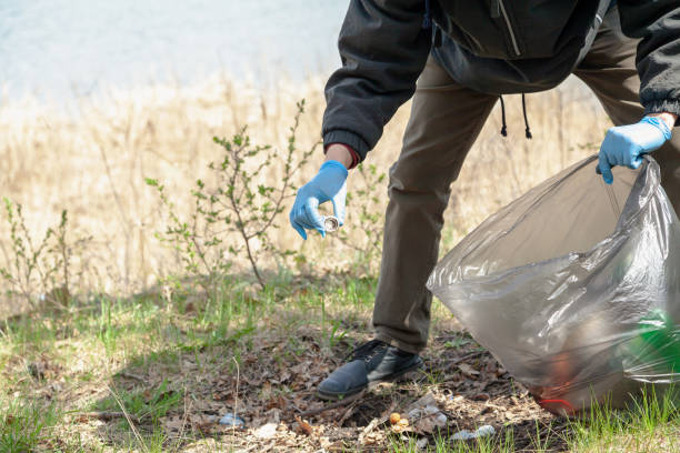 istock Man in gloves collects trash on river bank 1298314720