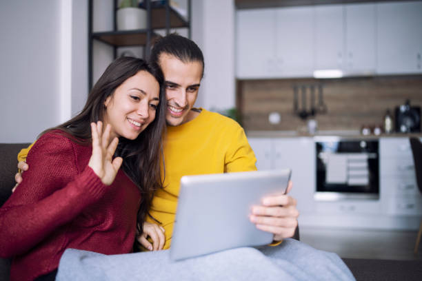 istock Young couple relaxing at home and having video call with digital tablet. 1298318170