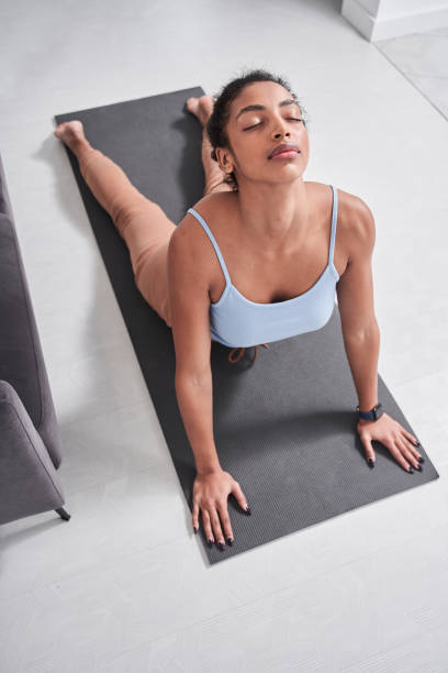 istock Woman in sportswear doing cobra pose while lying at the mat 1298318297