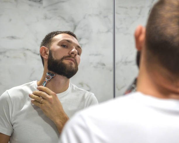 istock a young man is shaving his beard near the mirror 1298323763