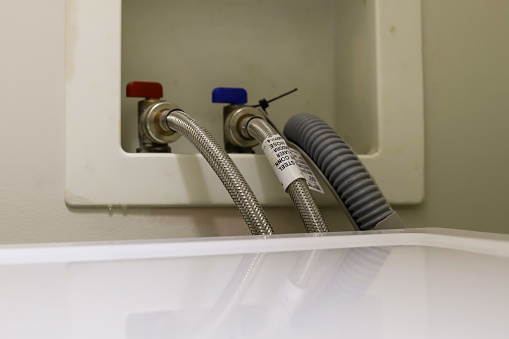A close-up image of a washing machine drain hose on a wall  in a laundry room