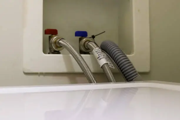 Photo of A close-up image of a washing machine drain hose on a wall  in a laundry room