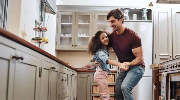 Shot of a man and his young daughter dancing in the kitchen at home