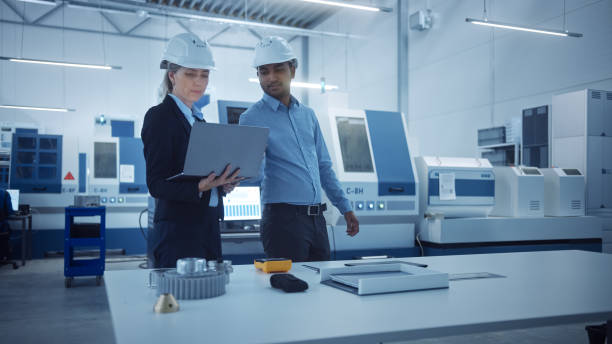istock Modern Factory with Professional Workers, Engineers, Managers Working on Production Line, Workshop Management, Optimization. Industrial Facility: Equipped with CNC Machinery and Robot arm Technology 1298327364
