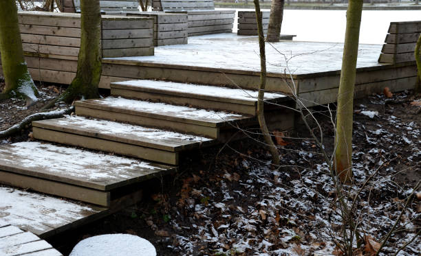 posti a sedere in legno con panchine rivestite in legno naturale nei boschi vicino all'acqua. terrazza sul ponte vicino allo stagno. tutto è un pezzo con articolazioni in inverno con un albero di neve nel buco del palco - non urban scene landscaped winter snow foto e immagini stock