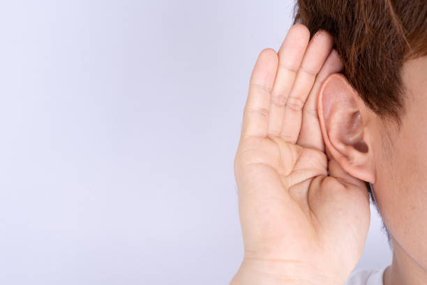 istock man hearing loss or hard of hearing and cupping his hand behind his ear isolate grey background, Deaf concept. 1298329445