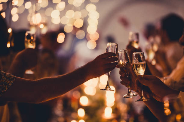 Celebratory Toast with String Lights and Champagne Silhouettes Numerous hands holding champagne flutes with champagne celebratory toast silhouettes cheers stock pictures, royalty-free photos & images